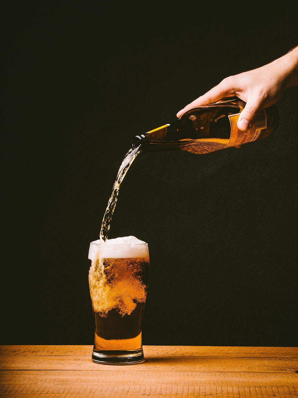 Golden beer with a thick foam crown on a wooden table