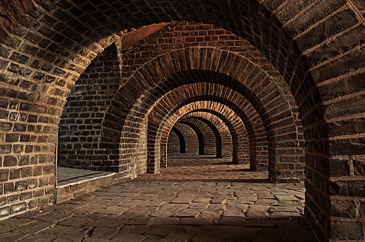 Receding arches of a brick-vaulted cellar with a cobbled floor